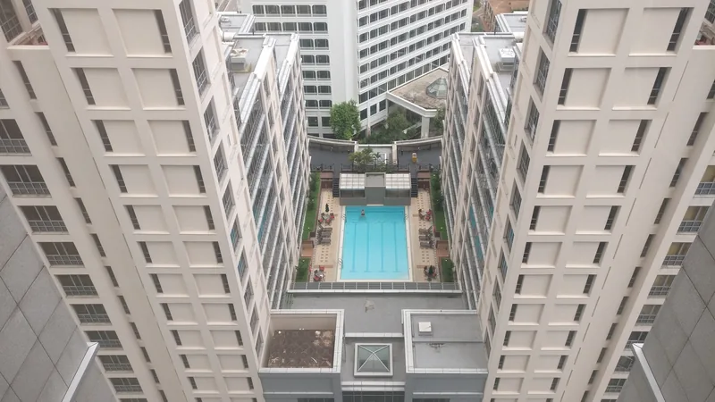 A view down between two white apartment towers to a swimming pool below