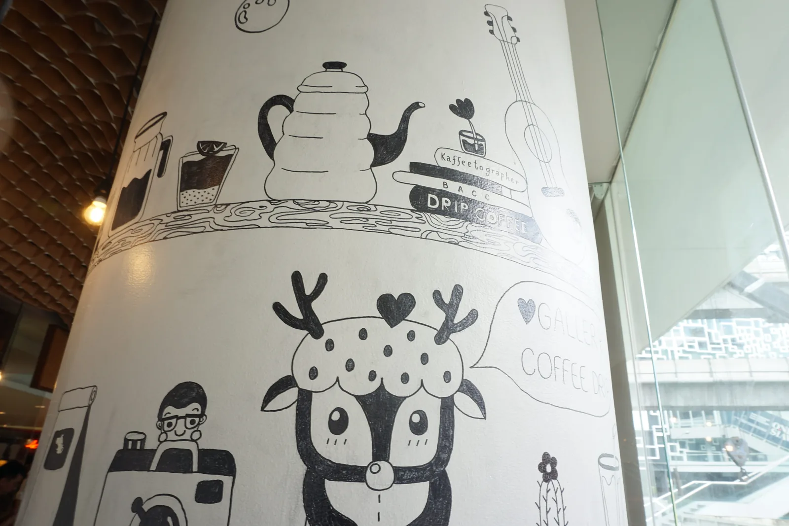 Ink drawings of a kettle, a deer and a camera on a white pillar