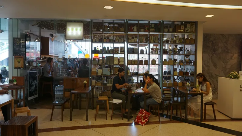 A cafe interior with a long shelf of glassware and people at the tables